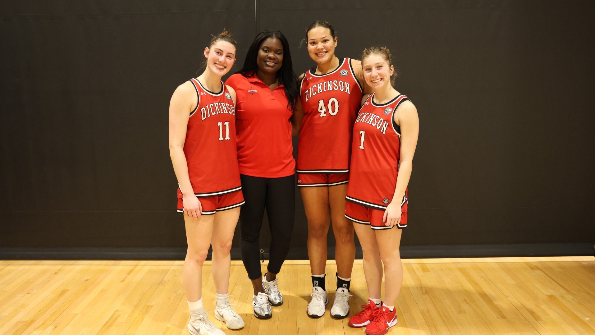 Head Coach Aby Diop with seniors Mia Chapman, Leah Dubin and Victoria Zerbe after winning her 100th career game by beating Washington College on 2-7-26