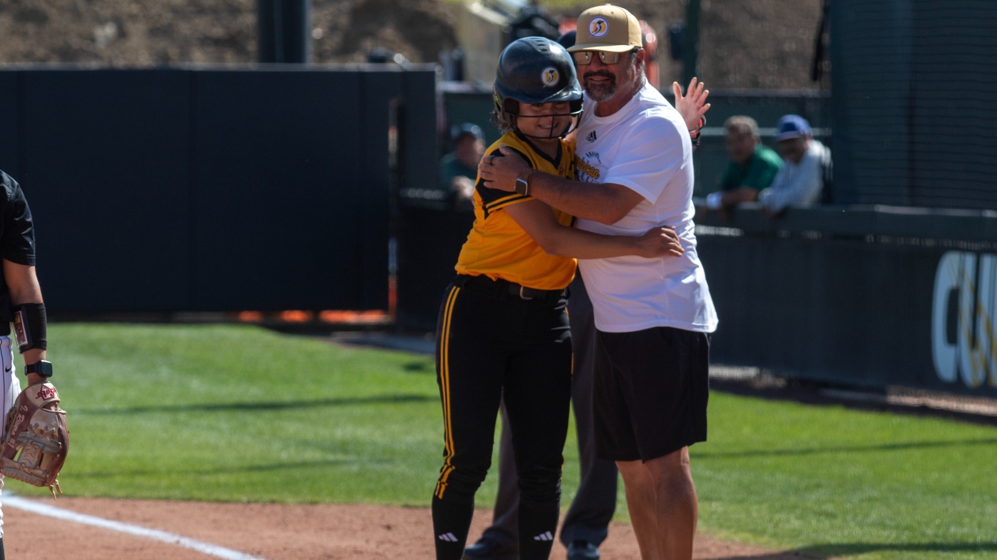 Caitlyn Perales shares a special moment with her uncle and assistant coach Bob Perales after a single in her final at bat as a Penguin