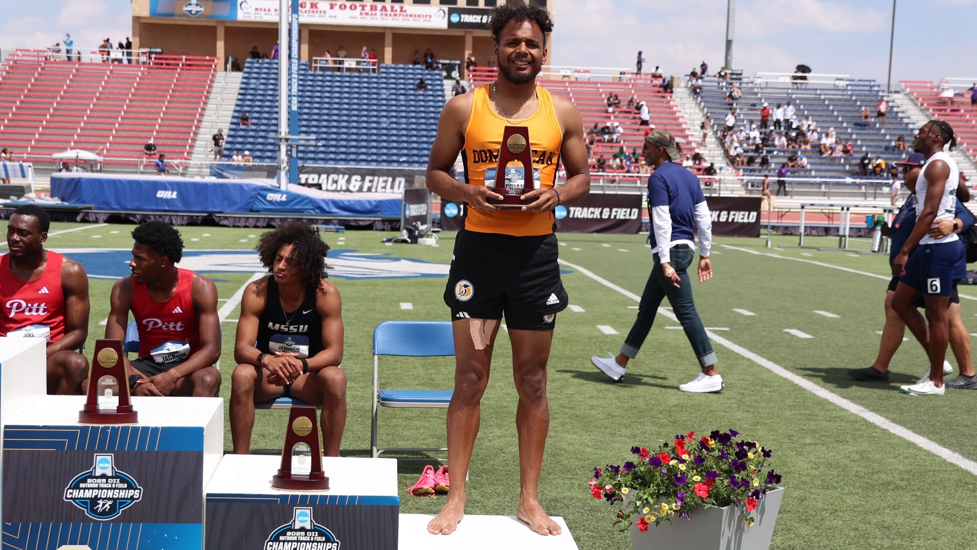 Adrian Aguirre poses on the podium with his All-American trophy