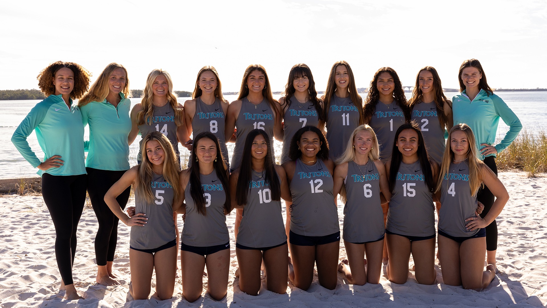 beach volleyball players and coaches posed for team picture at the beach  