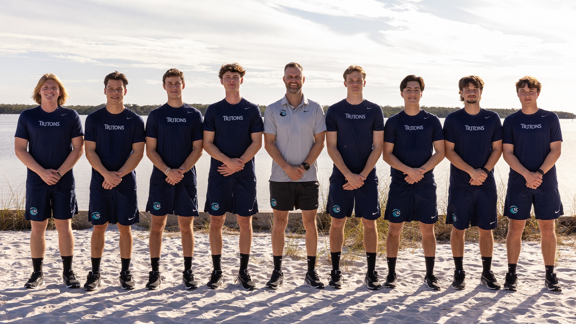 men's tennis players and coaches posed for team picture in gym 