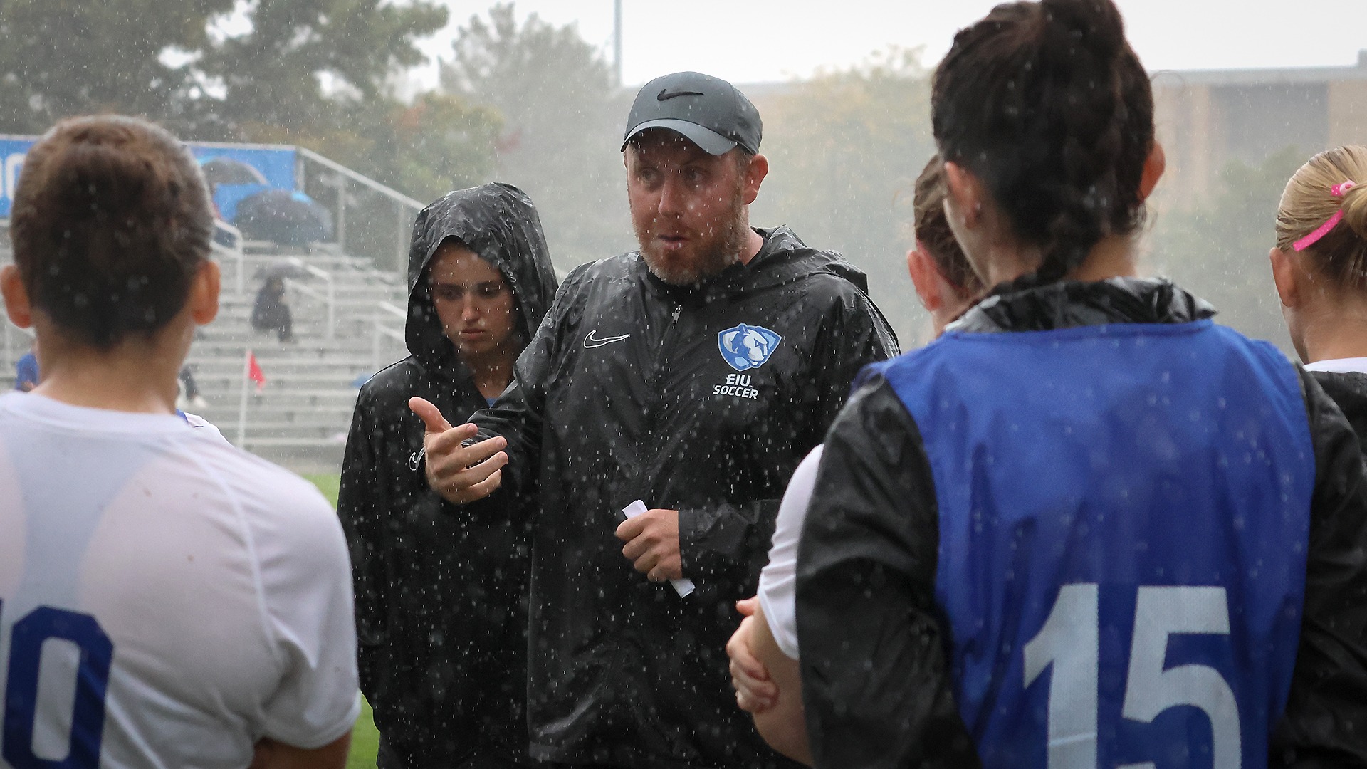 Rain Soaked Coaches for EIU talk in huddle on Thursday afternoon