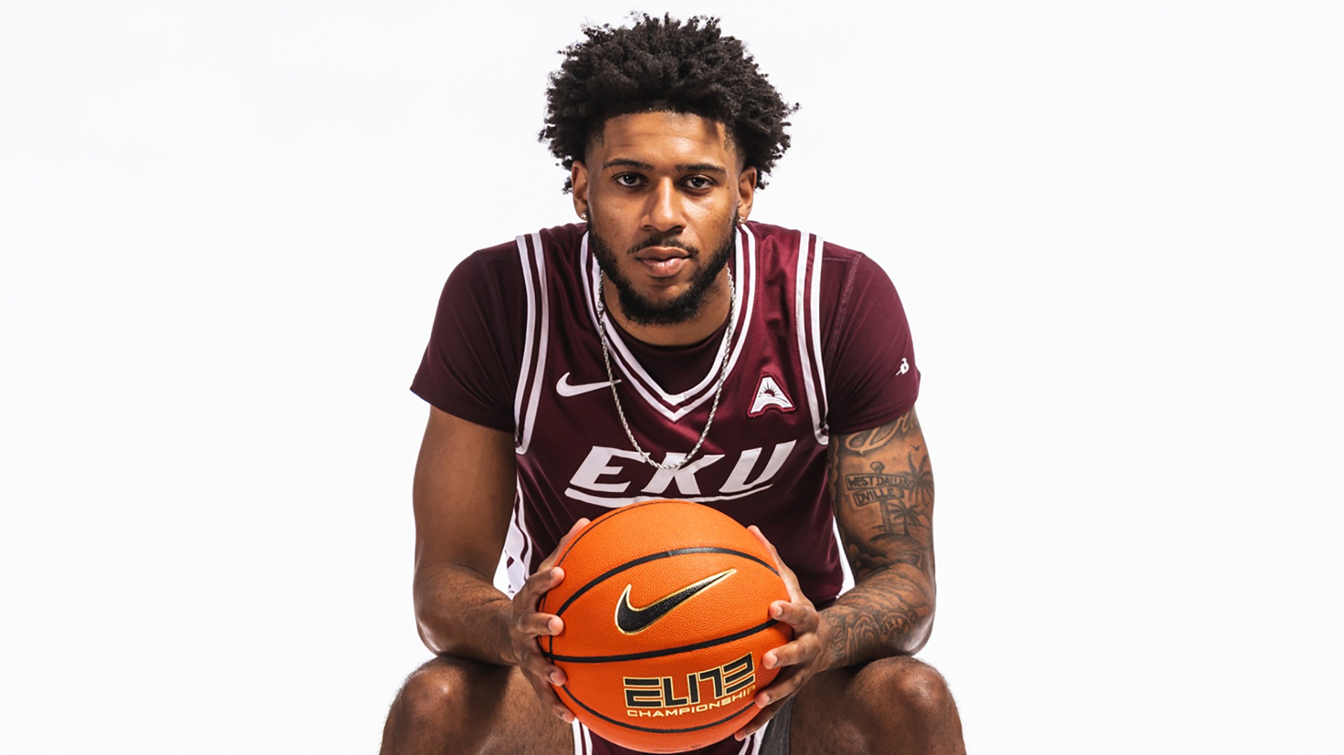 Aric Demings poses while sitting and holding a basketball