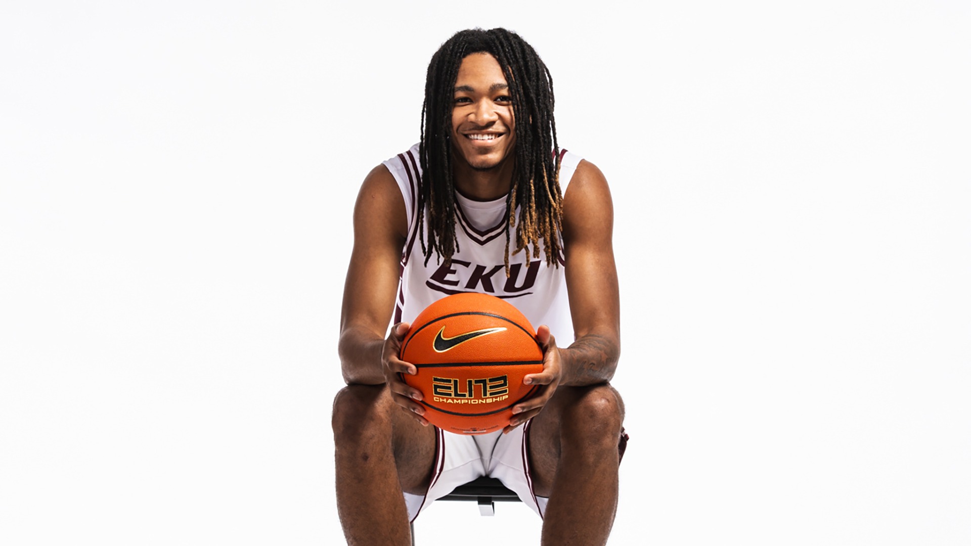 Justin McCarter poses while sitting down with a basketball