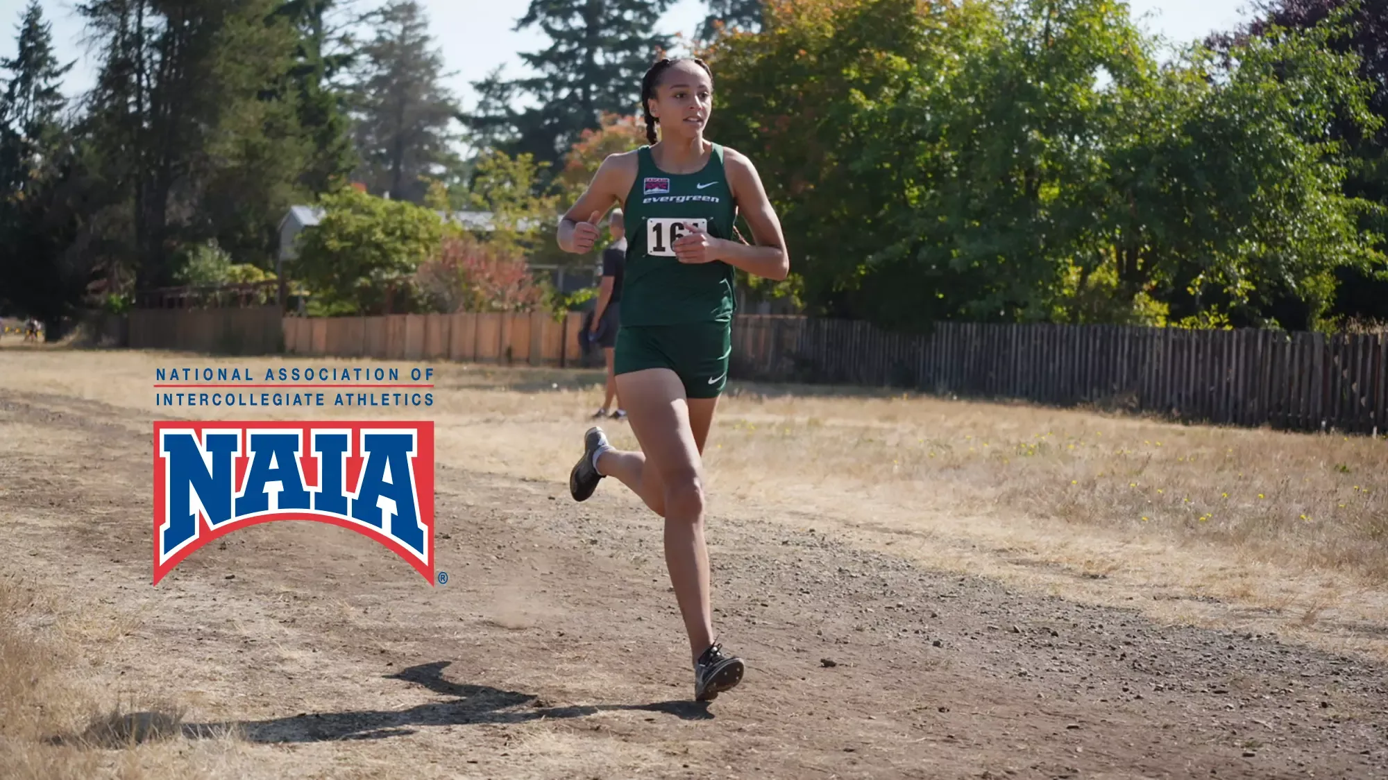 Alauna Carstens running next to the National Association of Intercollegiate Athletics logo