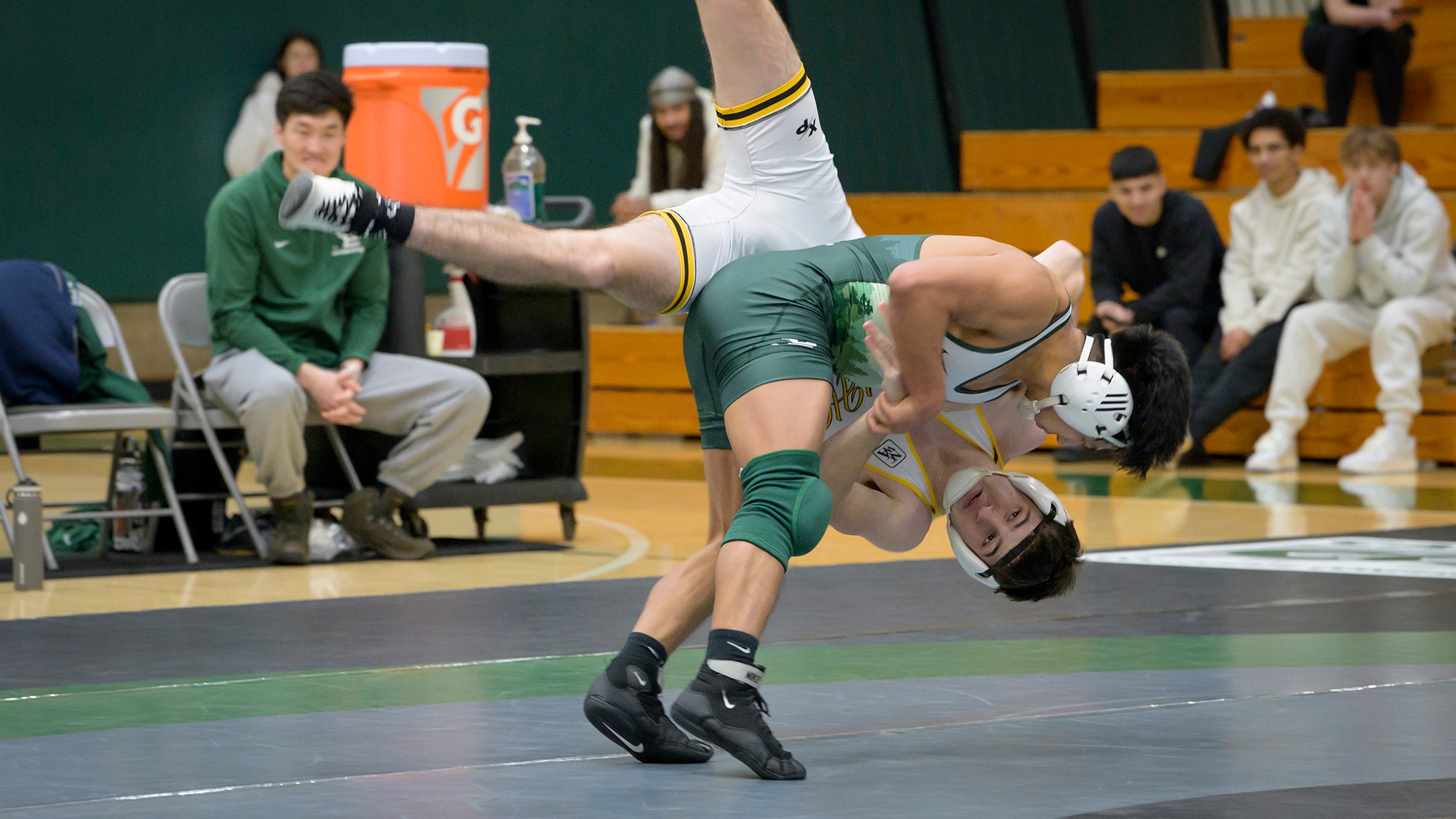 Horacio Godinez (wearing green) flips his opponent during a wrestling match.