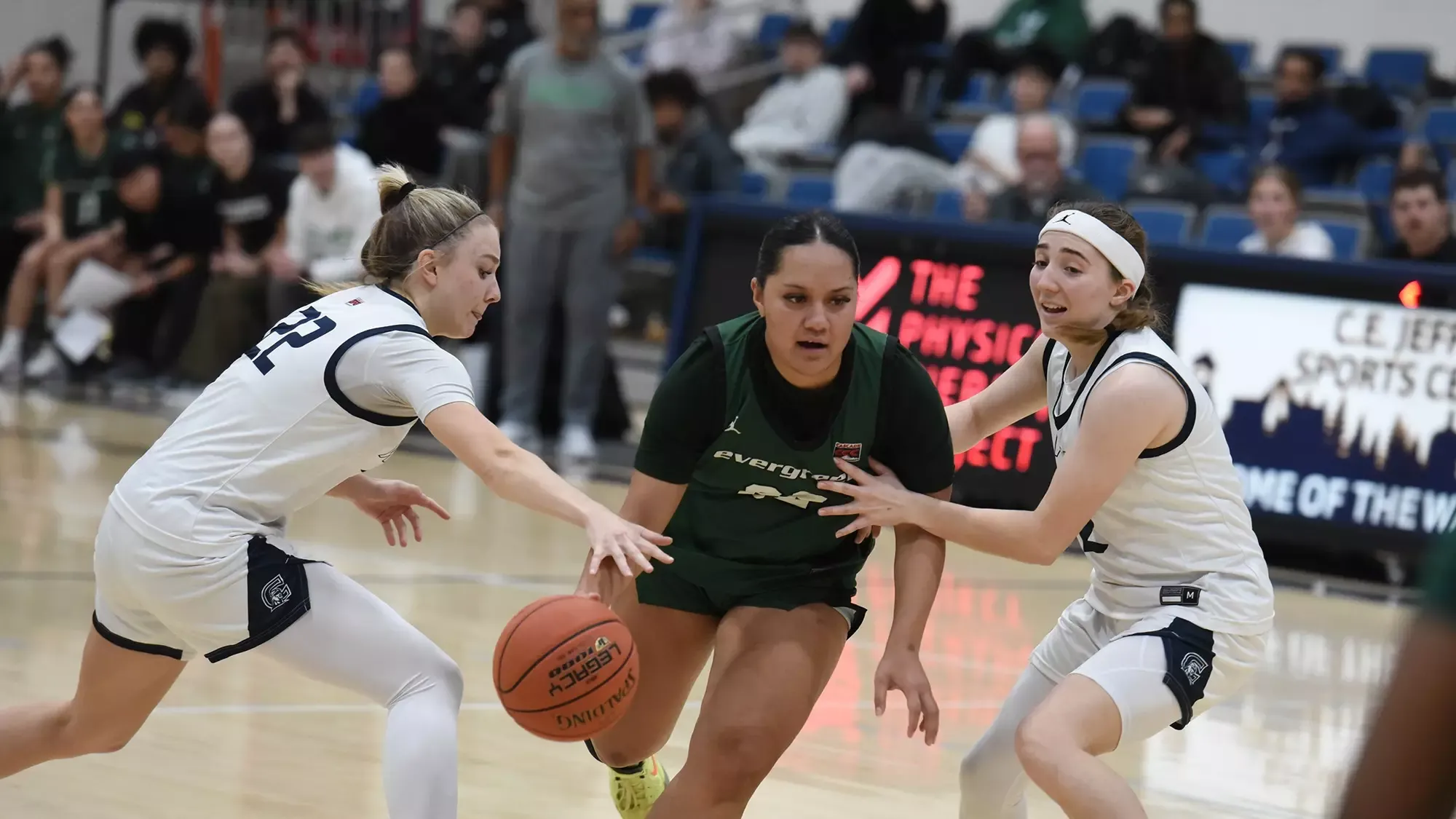 Amaya Afatasi dribbles the basketball between two defenders.