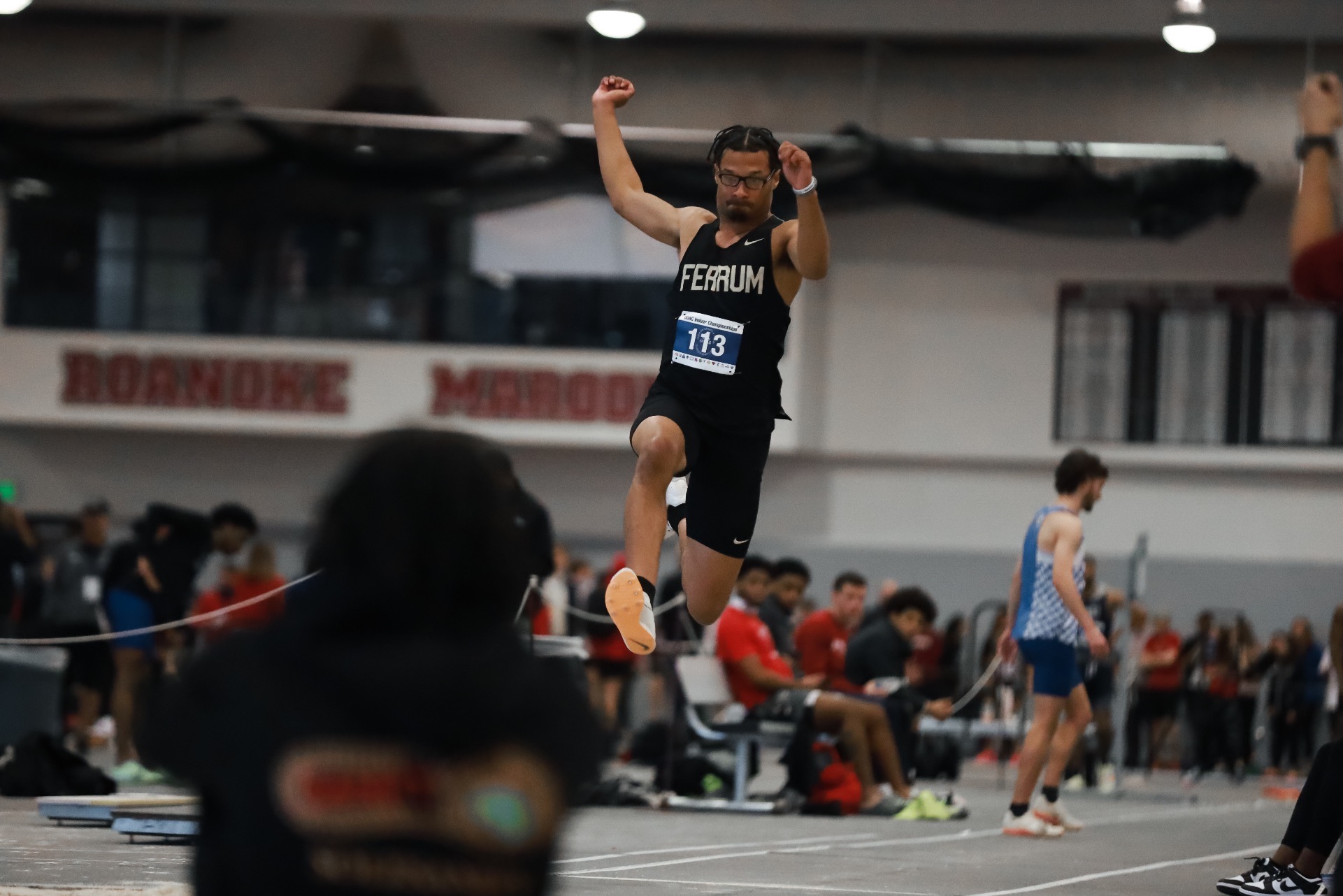 Deontae Lawson jumps in the air, in the triple jump event.