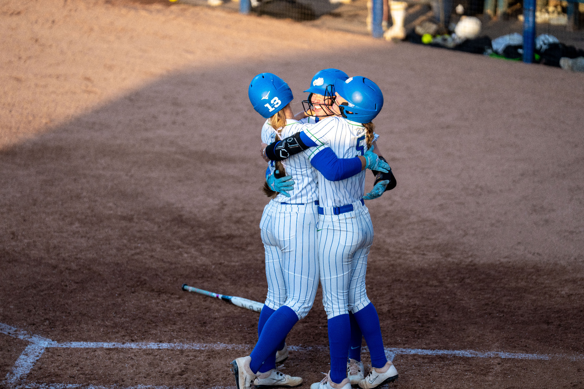 Mackenzie Leiti celebrates with Nikki Gibson and Sophie Wylie after hitting a solo home run against Queens