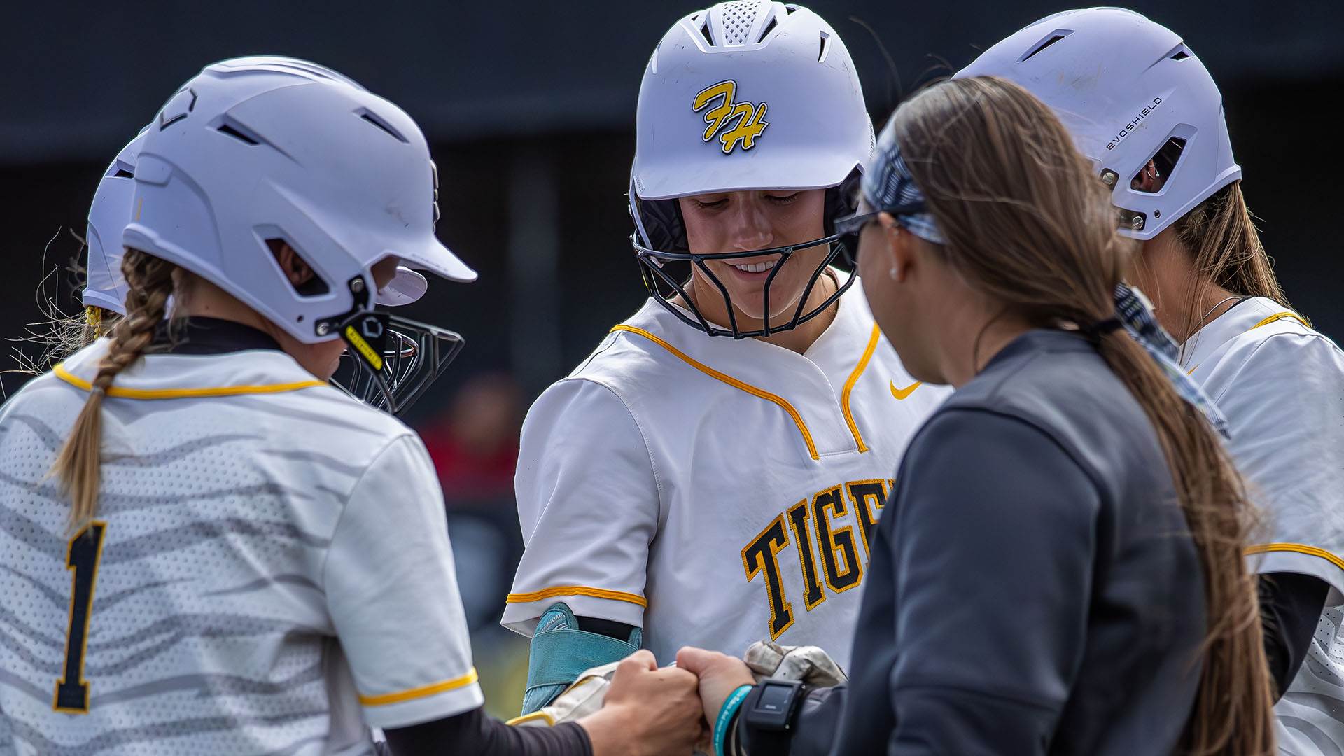 The FHSU softball team huddles around coach during a game against Newman