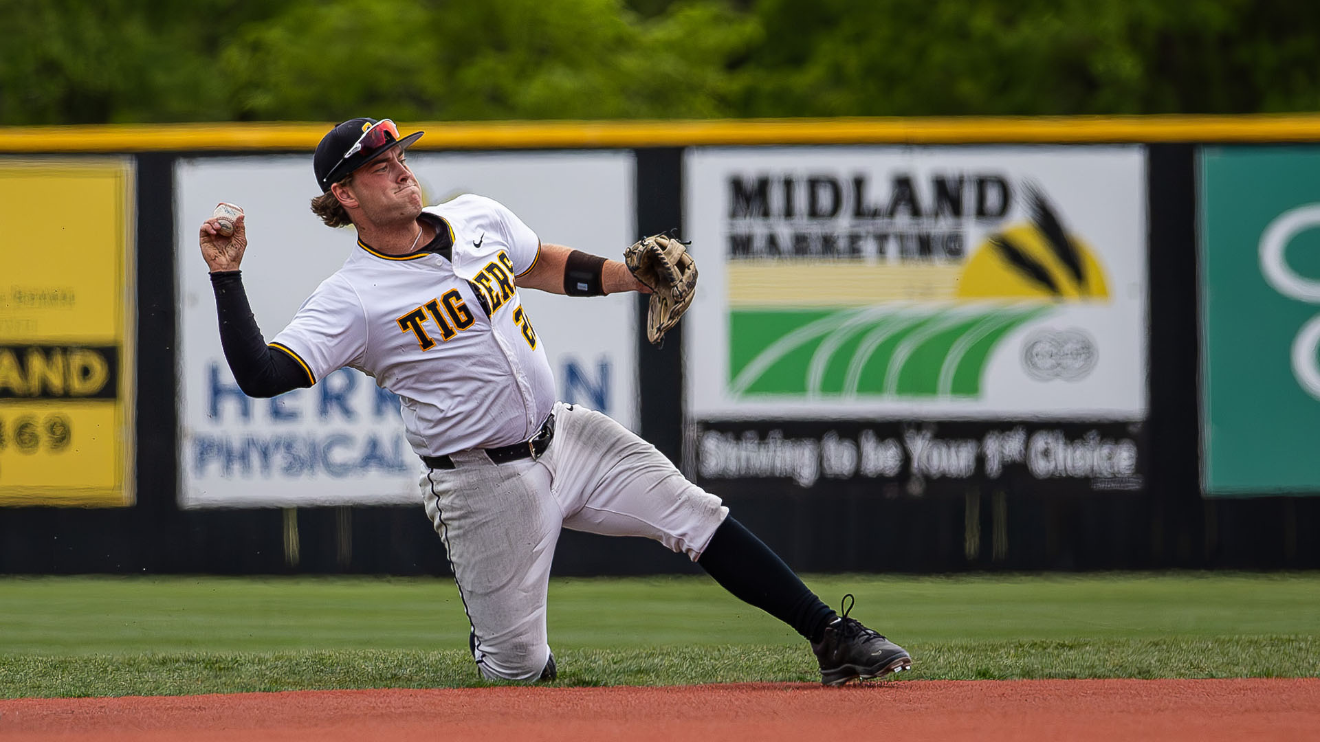 Derek Woolwine stops a ball and makes a throw to first base against Newman