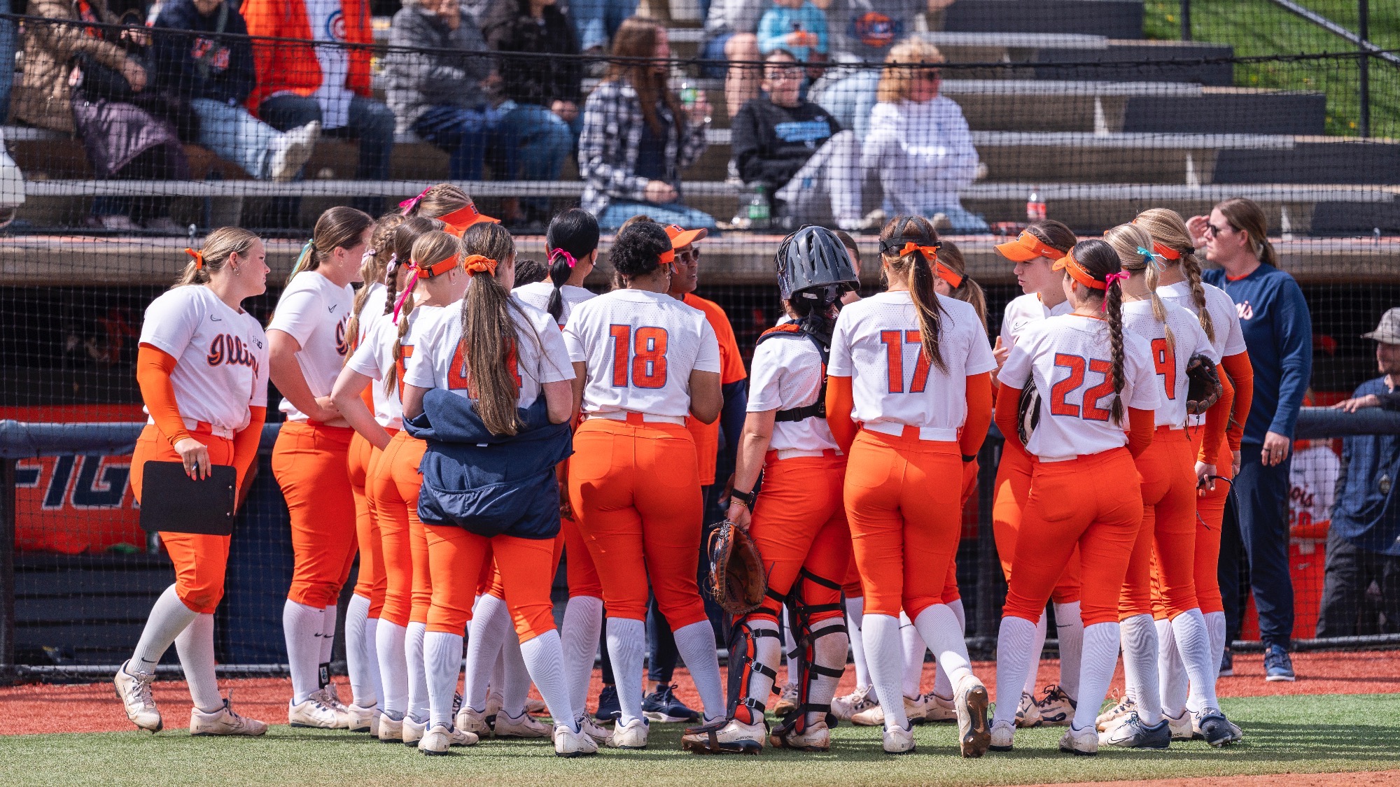 Illinois softball huddles in front of the dugout at Eichelberger Field in Urbana, Illinois.