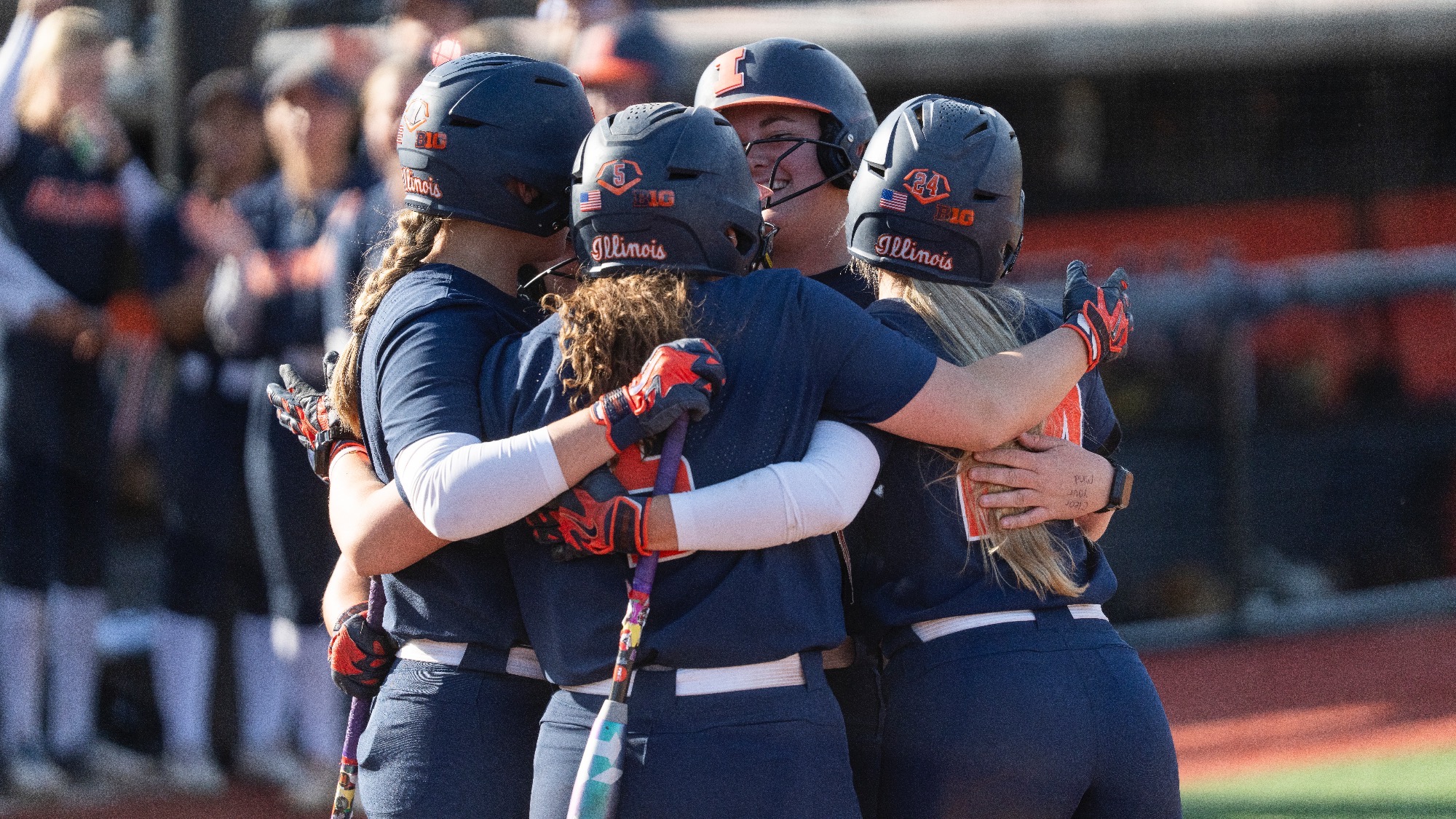 Eileen Donahue hugs her teammates after scoring a home run at Eichelberger Field in Urbana, Illinois.