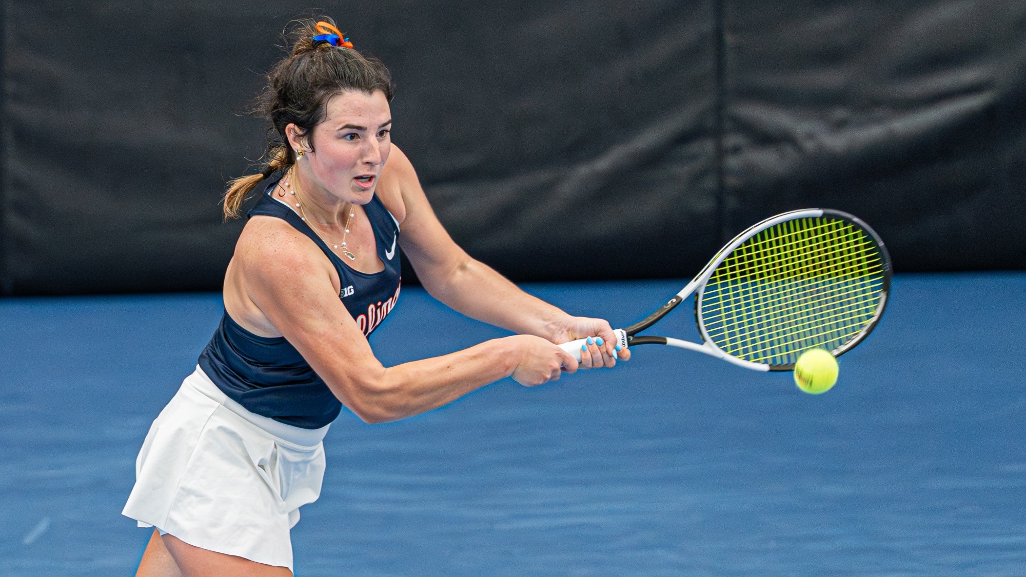 Tess Bucher hits a tennis ball in a match versus Michigan