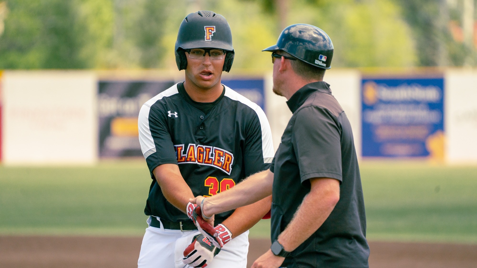 Eli Maddox gets congratulated by the first base coach