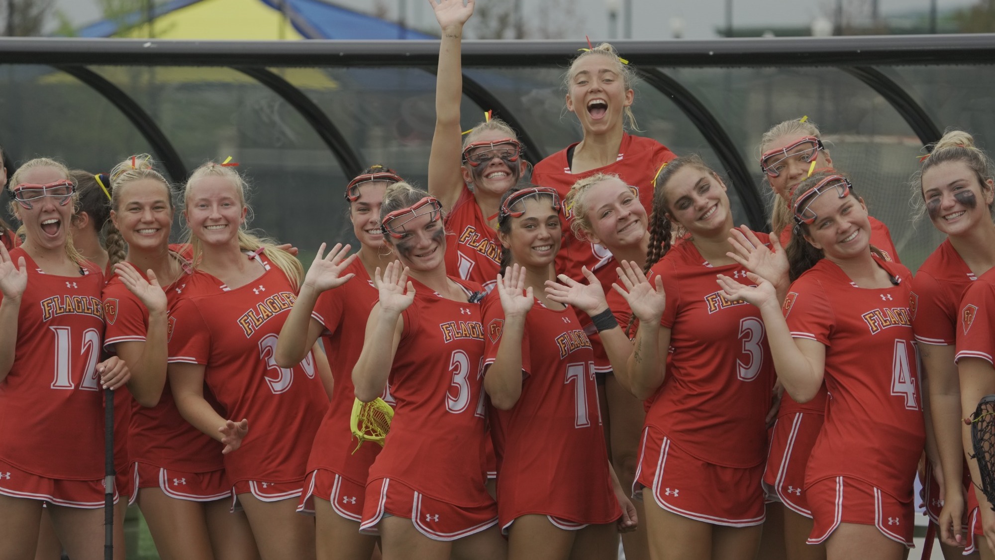 Women's lacrosse players pose for the camera after a win