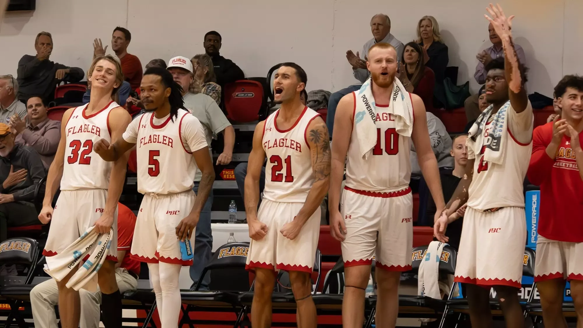 Flagler men's basketball players on the bench celebrate