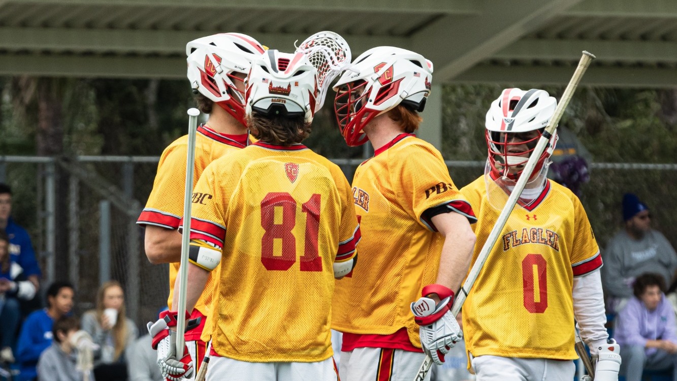 Flagler men's lacrosse players huddle together on the field