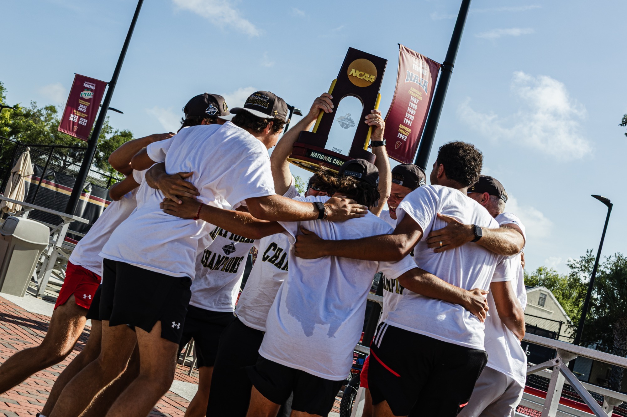 Men's tennis hoisting the trophy