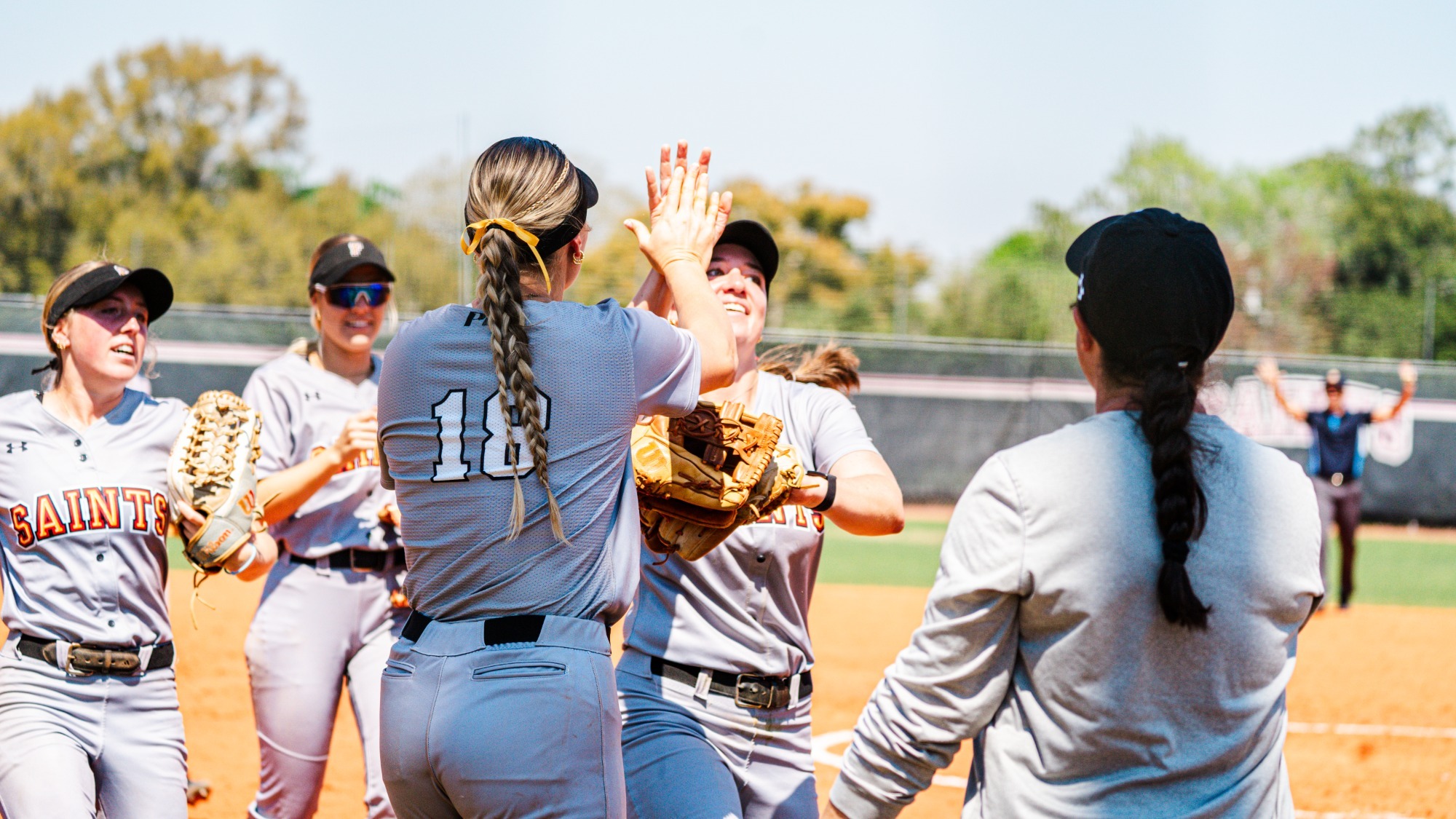 Flagler softball players celebrating in front of the dugout
