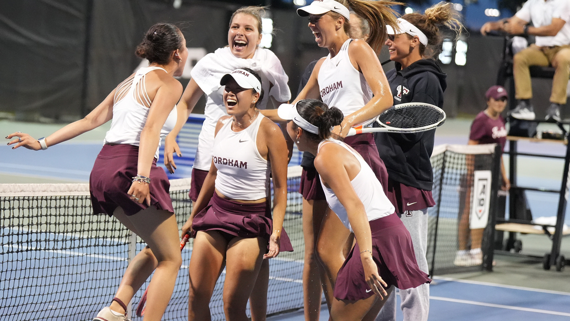 The Fordham women's tennis team celebrates its win over Davidson