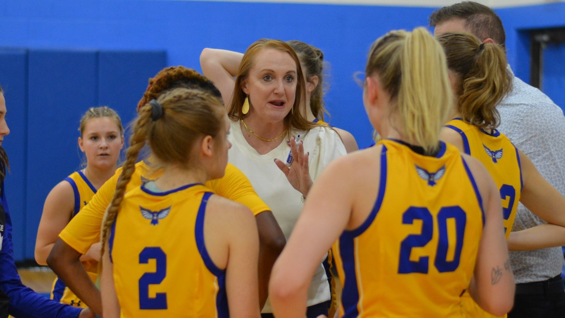 Fredonia State women's basketball head coach Nicole Bullock huddles with Hilbert players prior to joining the Blue Devils