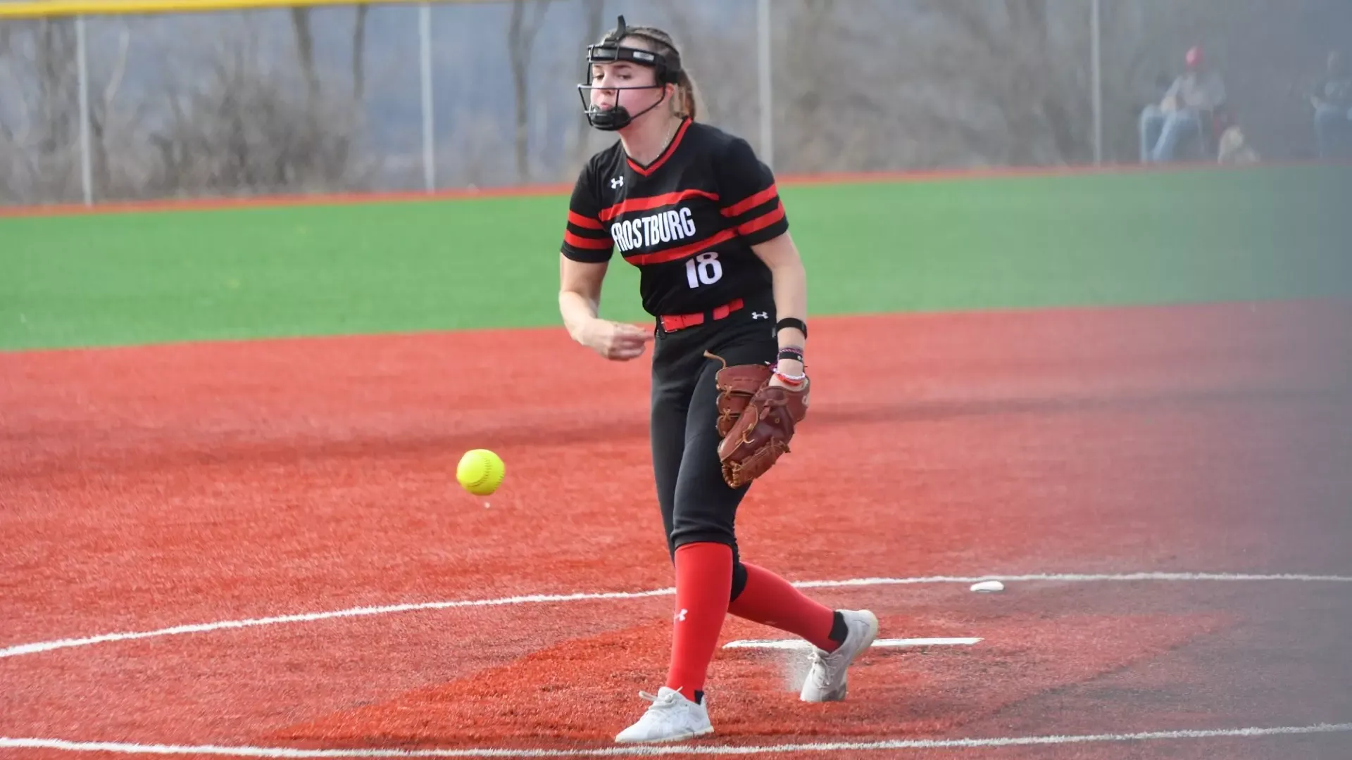 Frostburg Softball pitcher, number 18, Izzy Dietrich, throwing right-hand pitch on the mound. 