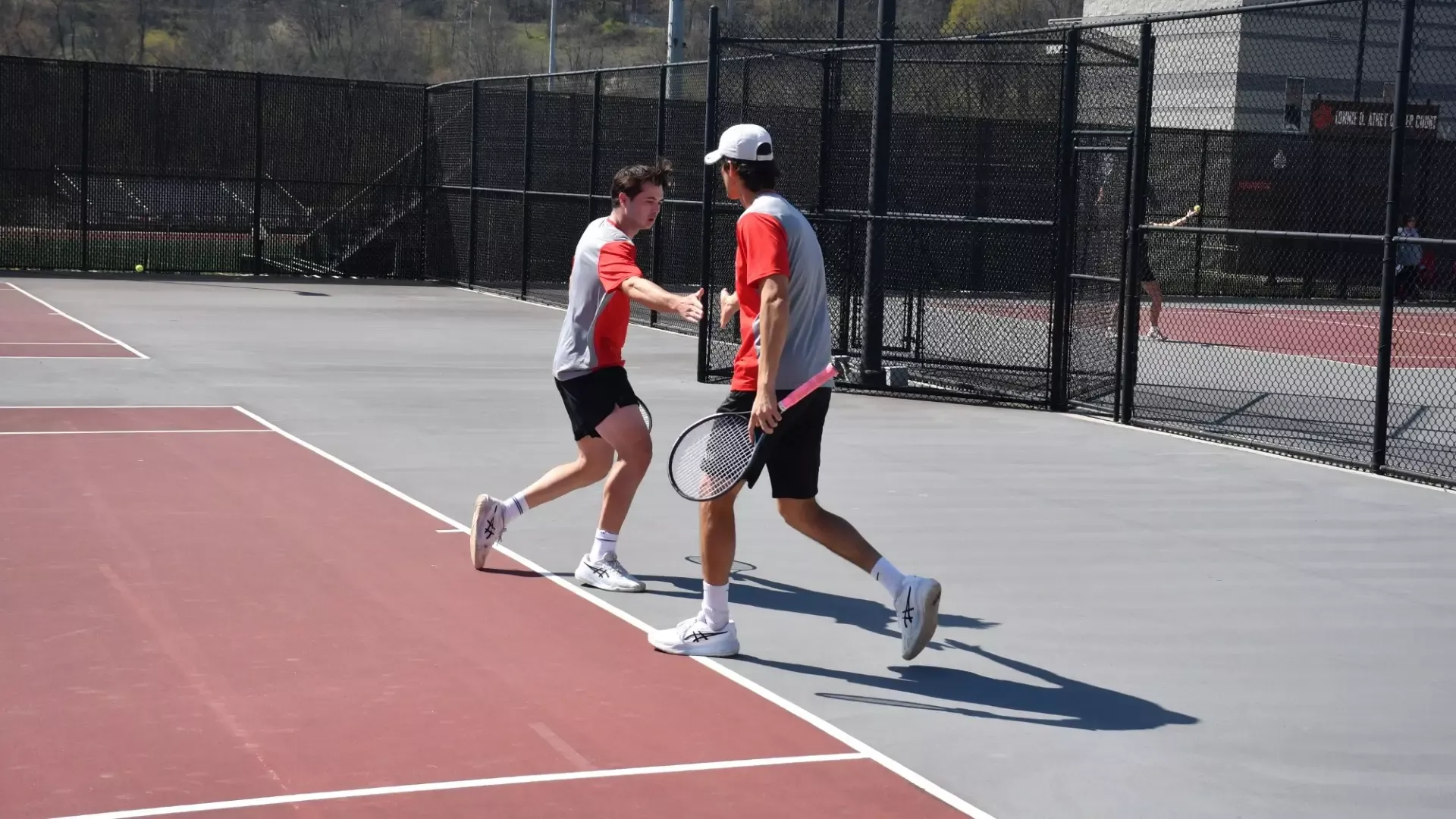 Frostburg men's tennis players, Gabriel Carrillo and Sergi Rodriguez high five each other in doubles match.