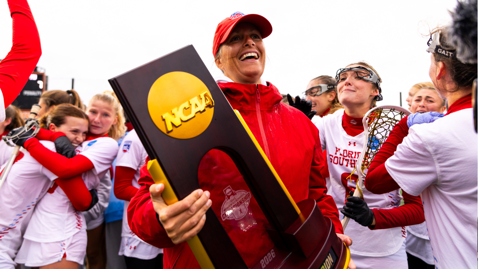 Head Coach Kara Reber holding 2026 National Championship trophy