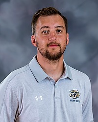 2023 MSOC Headshot - Kacey Monahan - Men's soccer intern looks towards the camera for a headshot. The intern is wearing a light blue Bison collared shirt. There is a gray backdrop behind the intern.