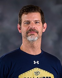 Gallaudet softball 2024 headshot Brian Van Bavel. The volunteer coach is wearing an navy blue long sleeve shirt with a GU Bison Logo on it. The volunteer coach is photographed with a gray background in the back.