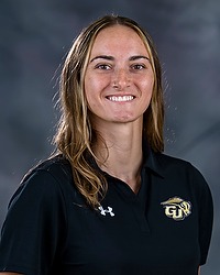 2024 XC Headshot - Hannah Wetzel- Men & women's cross country assistant coach looks towards the camera for a headshot. The coach is wearing a black collared polo shirt. There is a gray backdrop behind the coach.