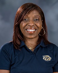 Gallaudet fall cheerleading 2024 headshot Tara Miles. The coach is wearing a blue bison collared polo shirt. The coach is photographed with a gray background in the back.