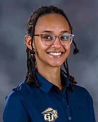 Gallaudet fall cheerleading 2024 headshot Isabelle Taveras. The assistant coach is wearing a blue bison collared polo shirt. The coach is photographed with a gray background in the back.