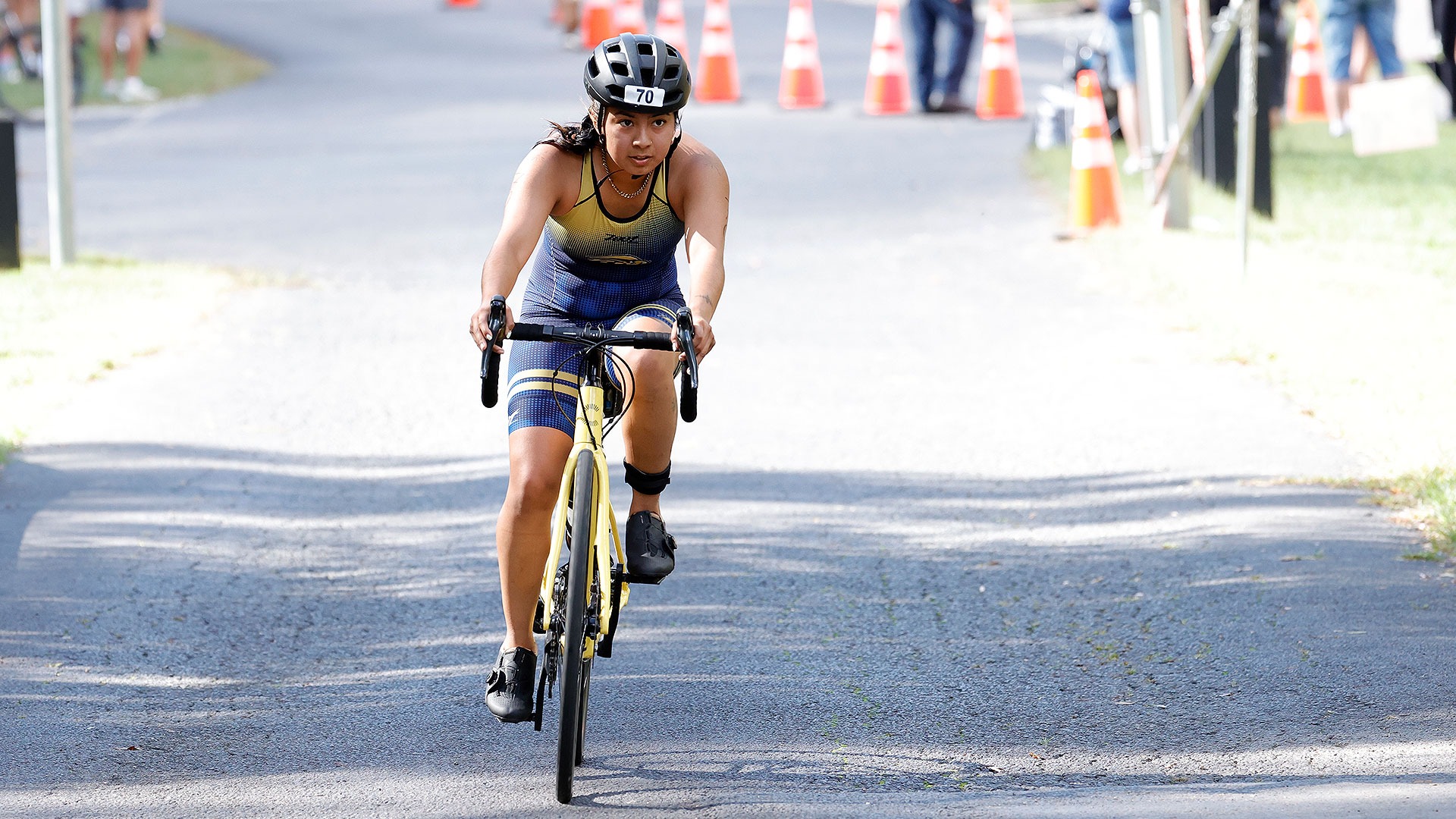 Gallaudet women's triathlon action photo of Jasmine Jimenez Lara riding a bicycle on a sunny day. 