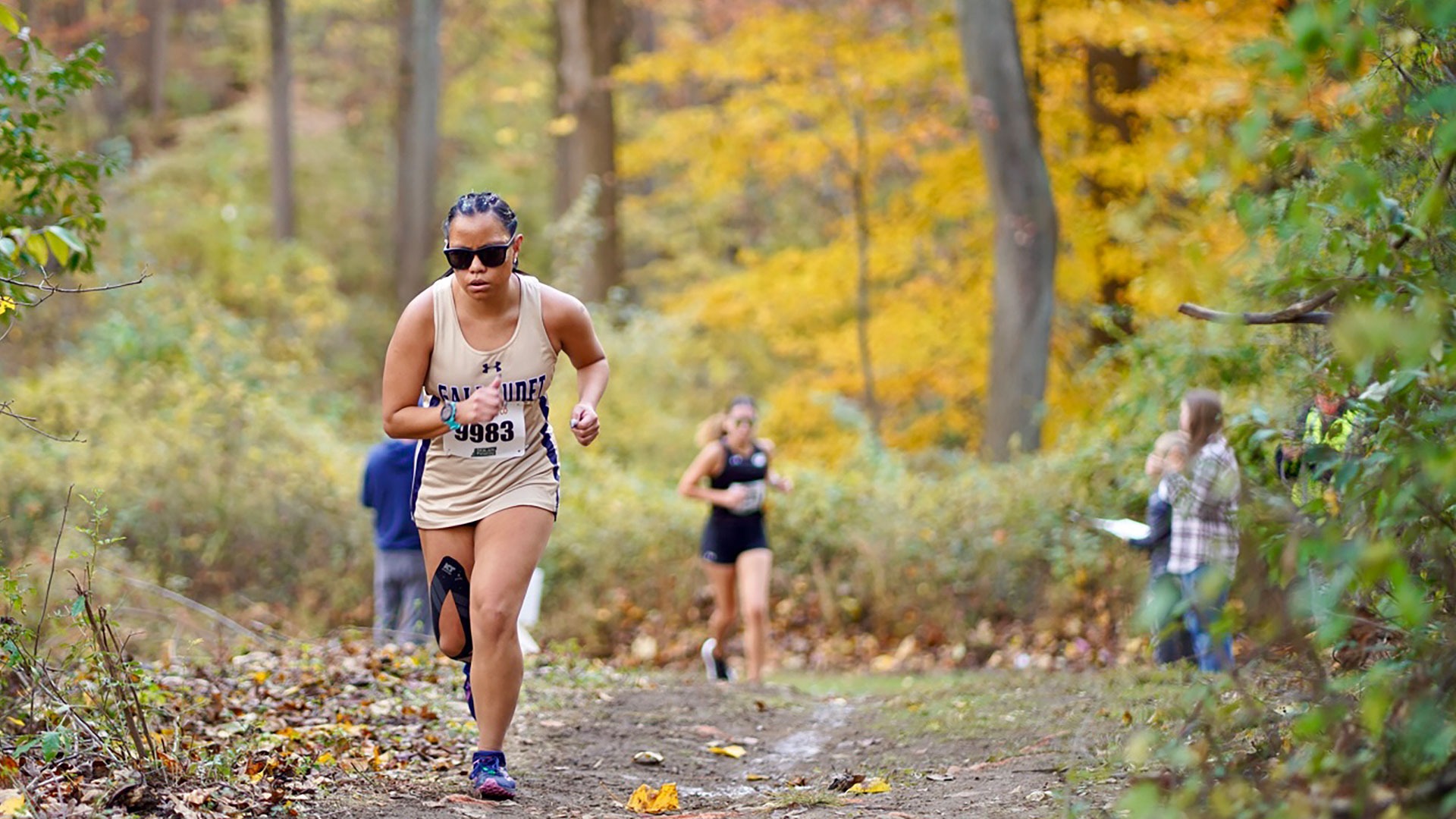 Gallaudet women's cross country runner Olivia Armstrong runs up a hill during the 2025 United East championship in the afternoon.