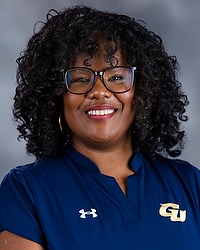 2025-26 Gallaudet University women's basketball faculty athletics mentor Felicia Williams headshot photo. she is wearing a navy blue polo shirt against a grey background.