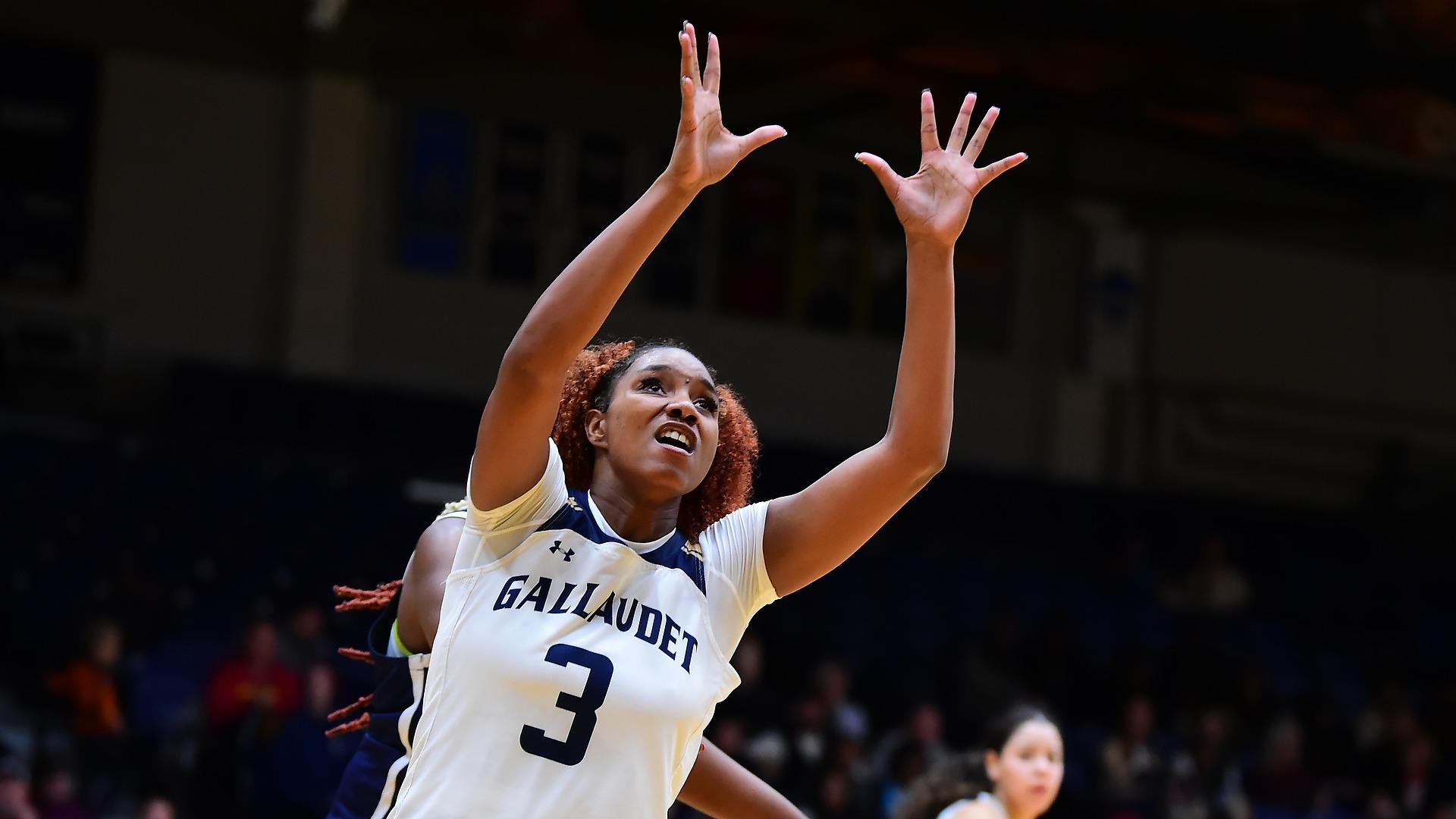 Gallaudet women's basketball player Natalie Greene is attemping to rebound the ball during a home game in the Field House against Washington Adventist University.