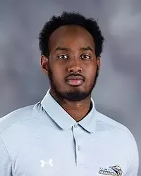 Gallaudet University men's basketball team manager Mahirwe John headshot photo. He is wearing a grey polo shirt against a grey background.