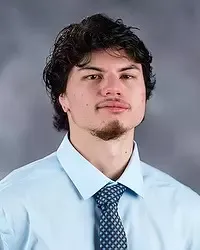 Gallaudet University men's basketball student assistant Malosi Viena headshot photo. He is wearing a light blue button down shirt and blue tie against a grey background.
