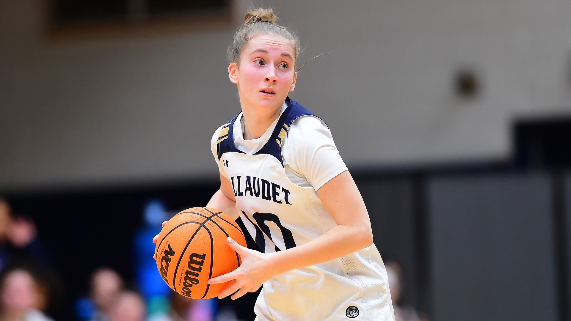 Gallaudet women's basketball player Seanna Baird holds the orange basketball during a home contest on this closeup photo as she looks for a teammate to pass the ball too. 