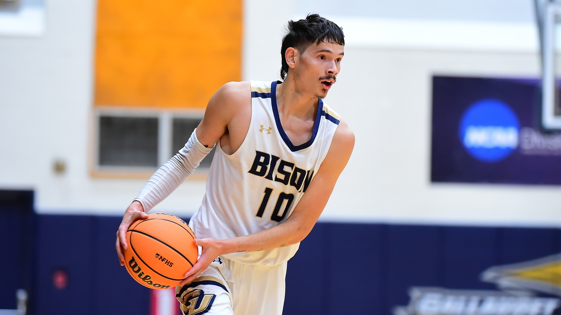 Gallaudet men's basketball player Jory Valencia dribbles the orange basketball on the outside of the arc in a home game in the Field House.