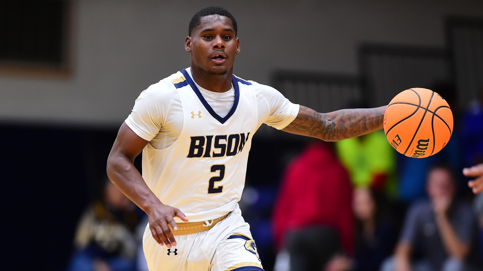 Gallaudet men's basketball player Brandon Washington dribbles an orange basketball up the court. The photo is cropped tightly on Brandon.