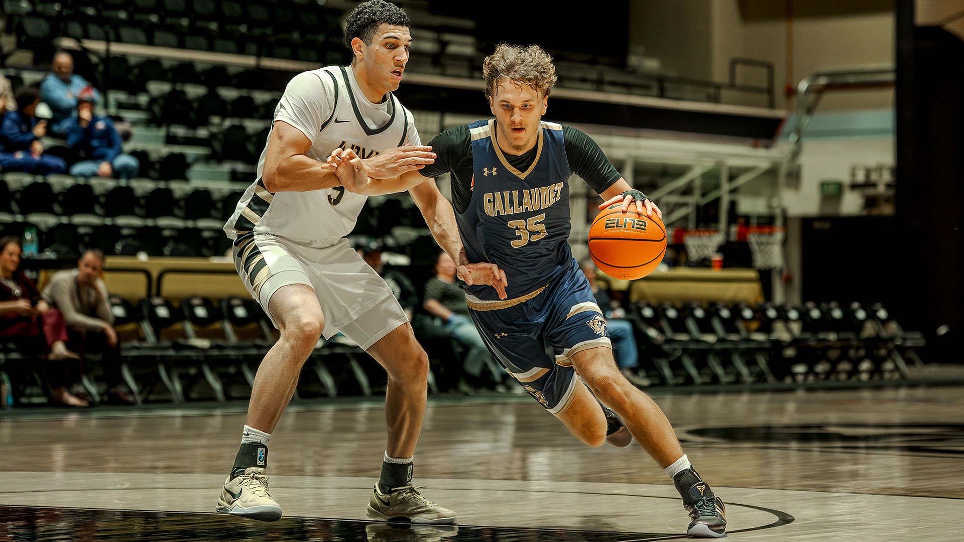 Gallaudet forward Jayden Orsi-Pedersen drives towards the basket as he dribbles an orange basketball past an Army West Point defender on the road.