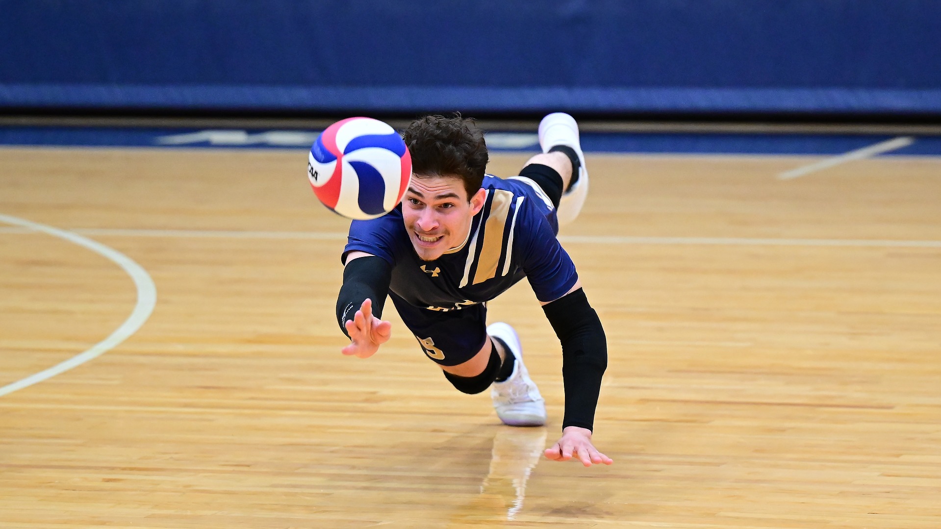 Gallaudet libero Elian Zfati makes a diving dig during a men's volleyball match. 