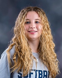 Softball headshot photo of Kate Meyer , who is looking towards the camera. A gray background is behind Meyer.