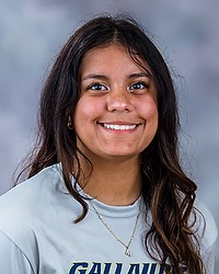FB Headshot - Mallory Morones manager looks towards the camera for a headshot. The manager is wearing a gray t-shirt. There is a gray backdrop behind the manager.