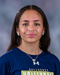 2025 WVB Headshot - Brittany Rivera Women's volleyball manager looks towards the camera for a headshot. The manager is wearing a blue long sleeve. There is a gray backdrop behind the player.