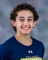 2025 WVB Headshot - Tamara Tadevosyan Women's volleyball manager looks towards the camera for a headshot. The manager is wearing a blue long sleeve. There is a gray backdrop behind the player.