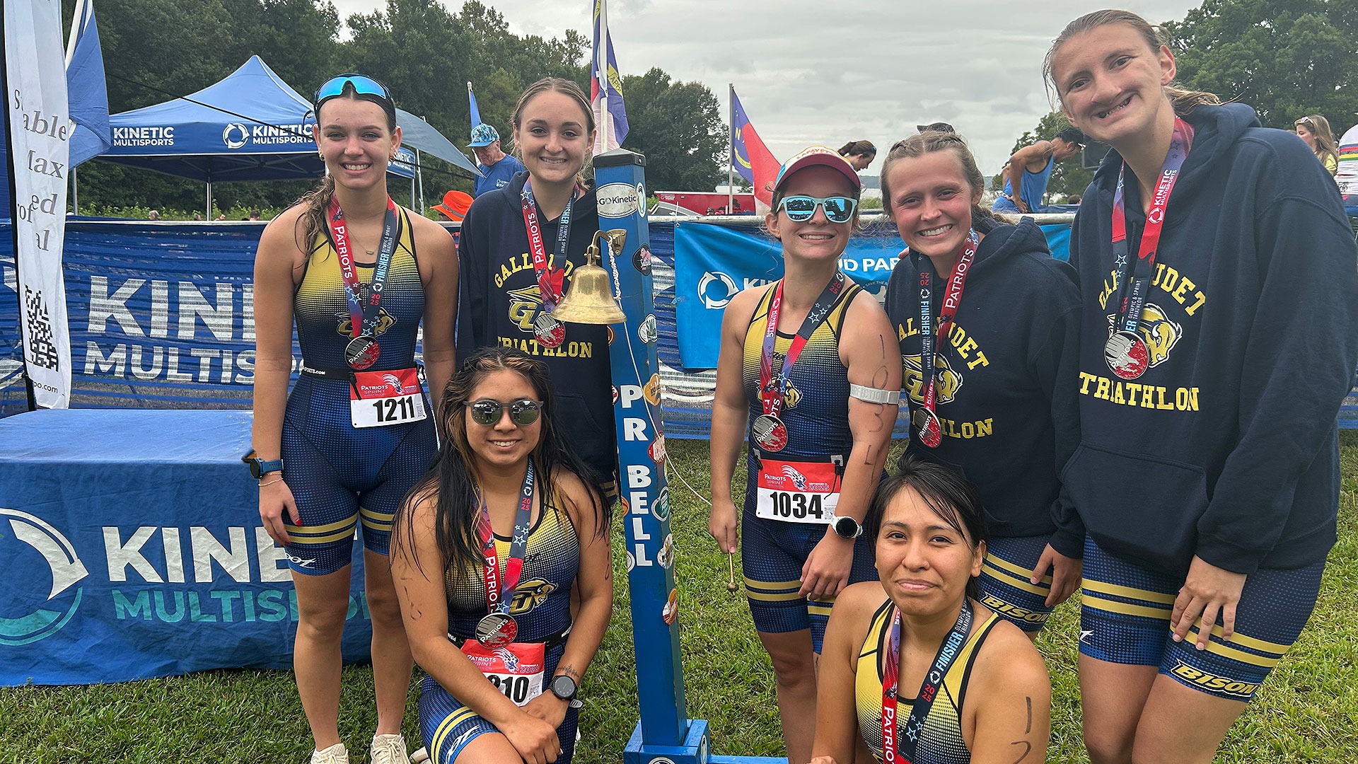 Gallaudet women's triathlon team pose for a group photo by the PR Bell at a race in Williamsburg, Va.